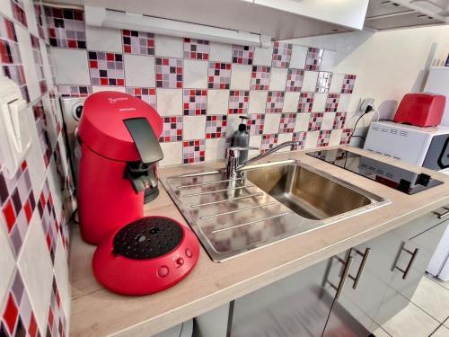 uma cozinha com um lavatório e um misturador vermelho em Superbe Type 2 - Cosy et Chaleureux em Bouguenais