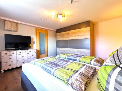 a bedroom with two beds and a flat screen tv at Ferienwohnung Am Bergmannsbrunnen in Schönheide