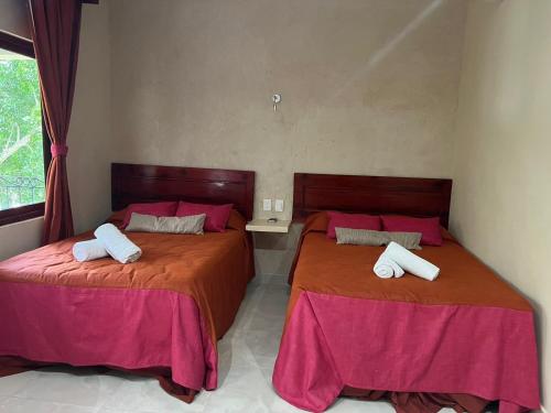two beds in a room with red sheets at Hotel Nojoch che in Cobá