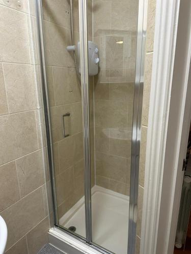 una doccia con porta in vetro in bagno di Somerton Studio a Londra