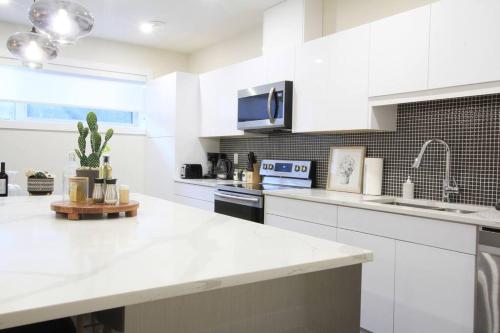 a kitchen with white cabinets and a white counter top at Executive Bsmt Suite, King Bed, 5 min to DT & Whyte Ave, Sleeps 6! in Edmonton
