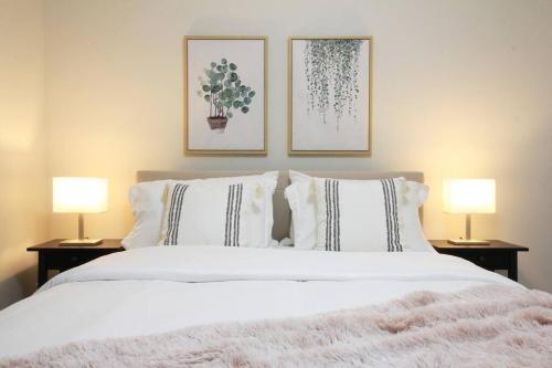 埃德蒙頓的住宿－Executive Bsmt Suite, King Bed, 5 min to DT & Whyte Ave, Sleeps 6!，一间卧室配有一张带两盏灯的大型白色床。