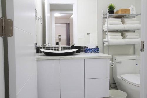La salle de bains blanche est pourvue d'un lavabo et d'un miroir. dans l'établissement Executive Bsmt Suite, King Bed, 5 min to DT & Whyte Ave, Sleeps 6!, à Edmonton