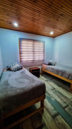 a bedroom with two beds and a wooden ceiling at Mauleuvu Outdoor, alojamiento bed and breakfast y actividades outdoor in Talca