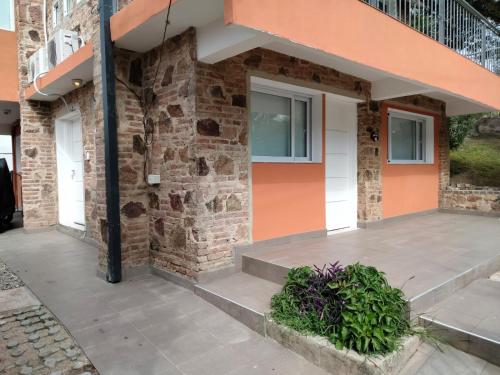 a brick building with a front porch with plants at Los Zorzales in Villa Carlos Paz