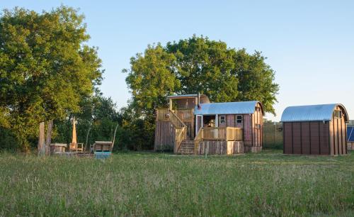 an old house and a shed in a field at Get Away Hide Away in East Dereham