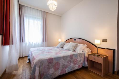 a bedroom with a bed and a chandelier at Grand Hotel Gortani in Arta Terme