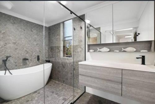 La salle de bains est pourvue d'une baignoire et d'un lavabo. dans l'établissement Manly family executive apartment, à Sydney