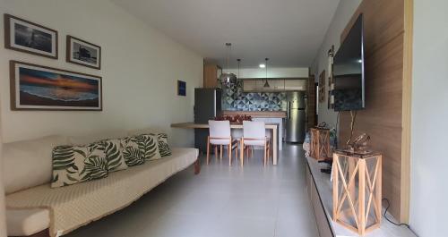 a living room with a couch and a table at Bangalô Tavarua Itacimirim Pé na areia in Itacimirim