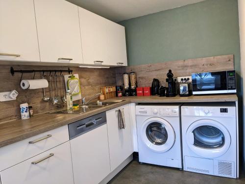 a kitchen with a washing machine and a microwave at S'Hüss Bed, appartement cosy in Herbitzheim