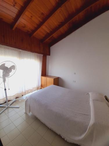1 dormitorio con 1 cama y ventana con ventilador en Tineo en Villa Gesell