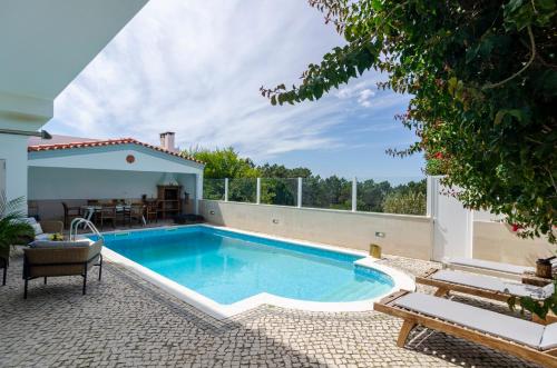 a swimming pool with a patio and a house at Trueby's Tapada - Amazing Villa with Pool & Ocean View By Silver Prop in Nazaré