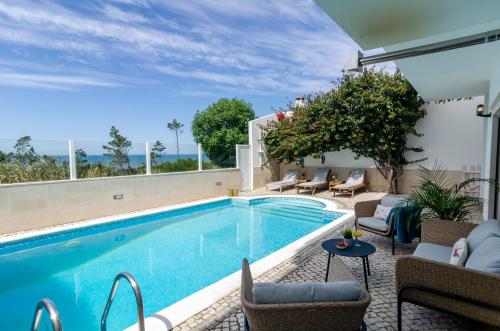 a swimming pool with chairs and a table next to a building at Trueby's Tapada - Amazing Villa with Pool & Ocean View By Silver Prop in Nazaré