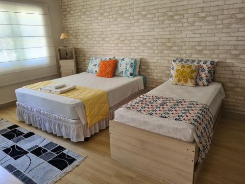 a bedroom with two beds and a brick wall at Guarujá Comfort & Design in Guarujá
