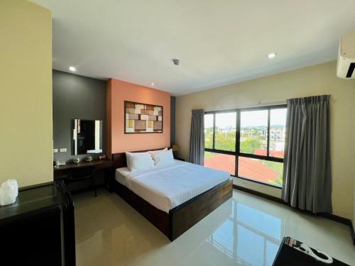 a bedroom with a bed and a television and a window at Ma Chic & Cozy in Lampang