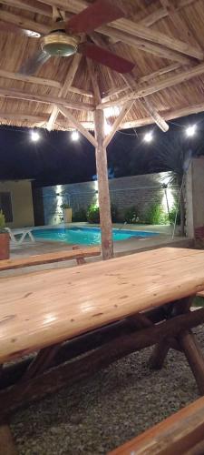 a wooden bench under a roof with a swimming pool at el descanso in San Antonio de Areco