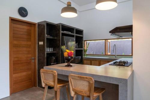 a kitchen with a large island with chairs and a counter at Villa Ikris - tranquil oasis in the heart of Canggu in Canggu