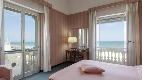 a bedroom with a bed and a balcony with the ocean at Hotel Esplanade in Pescara