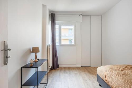 Schlafzimmer mit einem Bett, einem Tisch und einem Fenster in der Unterkunft Appart spacieux près de la Seine in Sartrouville