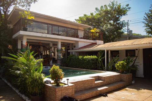 a house with a swimming pool in front of it at Hostel La Botella de Leche - Tamarindo in Tamarindo