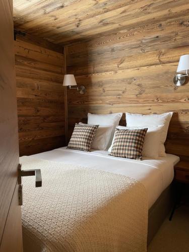 普華露的住宿－Le Lodge de Molanes - Pra Loup 1500，一间卧室设有木墙和一张带枕头的床。