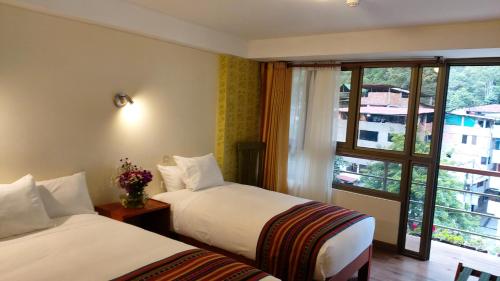 a hotel room with two beds and a window at Hotel Pucara Machupicchu in Machu Picchu