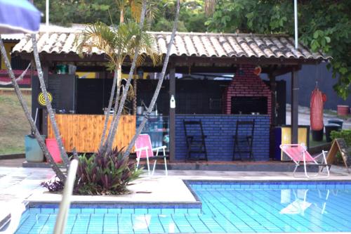 a swimming pool with chairs and a house with a fireplace at Das Marias Hostel in Lagoa Santa