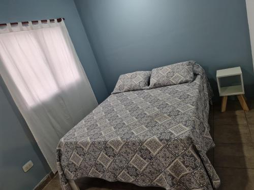 1 dormitorio con 1 cama con edredón y ventana en CasaBlanca alq. Deptos en San Salvador de Jujuy