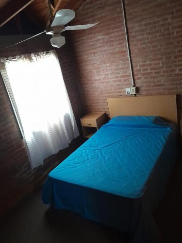 Un dormitorio con una cama azul y una ventana en Samaypata en Mina Clavero