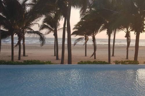 a view of a beach with palm trees and a swimming pool at Precioso departamento en Acapulco Diamante in Acapulco