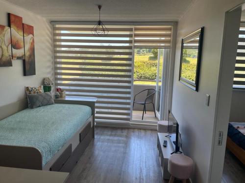 Schlafzimmer mit einem Bett und einem Fenster mit Jalousien in der Unterkunft departamento excelente ubicacion in Puerto Montt