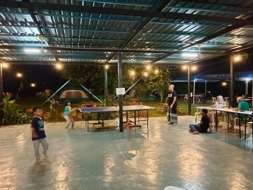 a group of people standing around a ping pong table at Outworld Basecamp in Gopeng