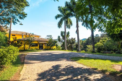 an empty road in front of a house with palm trees at Hotel Fazenda Minas Real in Simão Pereira