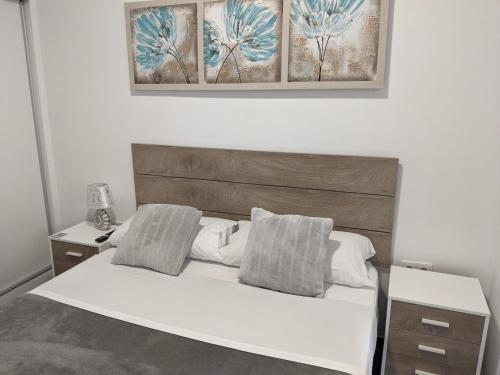 1 dormitorio con cama blanca y cabecero de madera en Pension Susita, en Alicante
