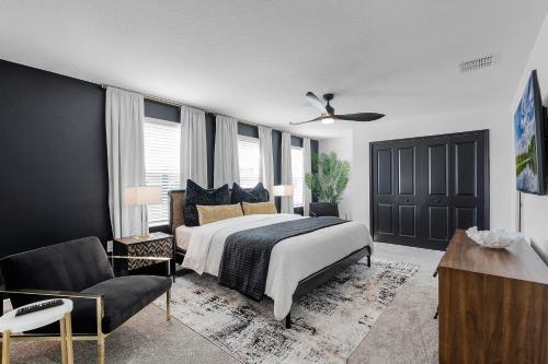 a bedroom with a bed and a chair and a ceiling fan at Disney Dream Vacation Home by Disney in Kissimmee