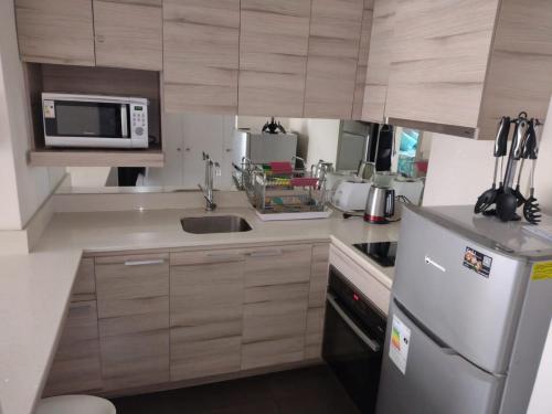 a kitchen with a refrigerator and a microwave at 2 Poniente con 3 Norte HERMOSOS Departamentos in Viña del Mar