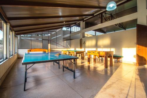 a ping pong table in a room with tables and chairs at Hotel Fazenda Minas Real in Simão Pereira