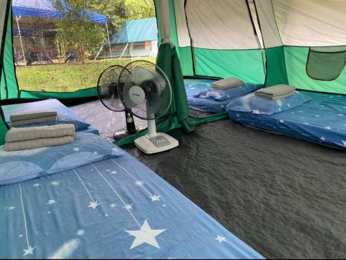 a tent with two beds and a fan in it at Outworld Basecamp in Gopeng