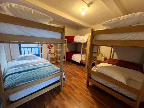two bunk beds in a room with wooden floors at The Sleepy Mouse in Cusco