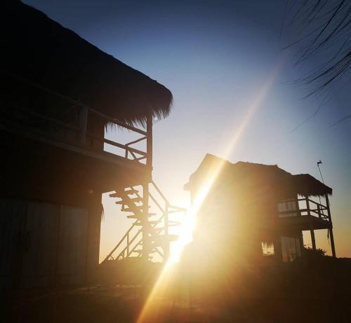 a sun is setting behind a building with the sun shining at Kite Nômade in Arraial do Cabo