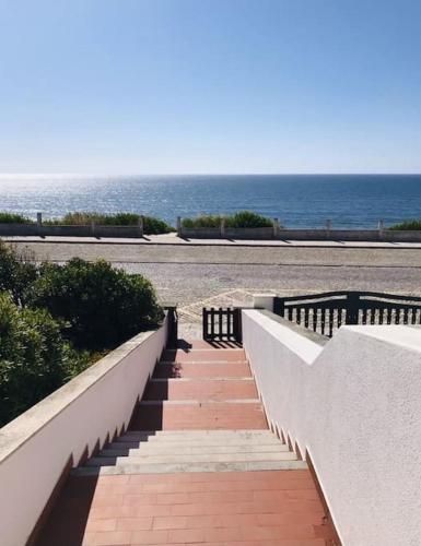 a staircase leading down to a beach with the ocean at Casinha do mar in Marinha Grande