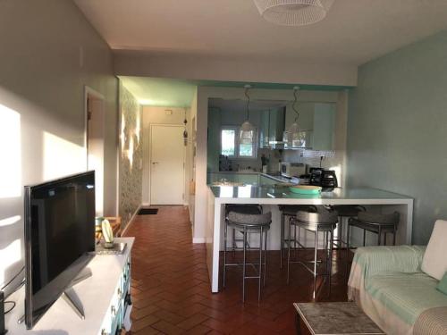 a living room with a kitchen and a bar with stools at Casinha do mar in Marinha Grande