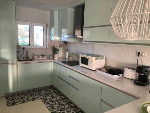 a kitchen with white cabinets and a microwave at Casinha do mar in Marinha Grande