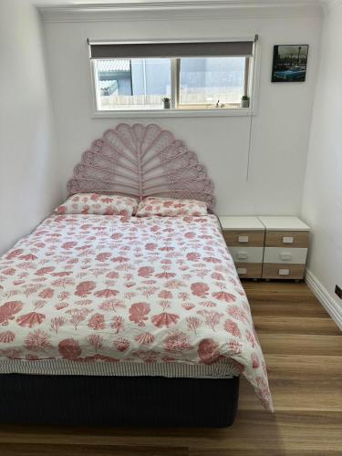 a bedroom with a bed with a floral bedspread and a window at Oakleigh Private unit in Oakleigh