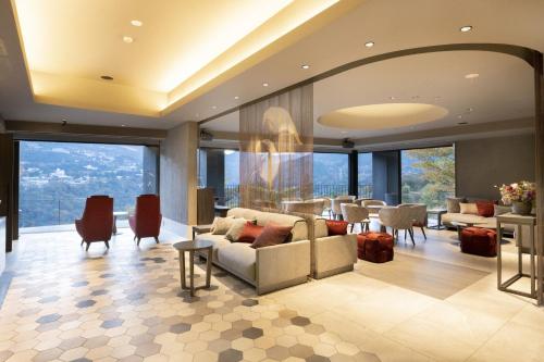 a living room with a couch and tables and windows at HAKONE NICA in Hakone
