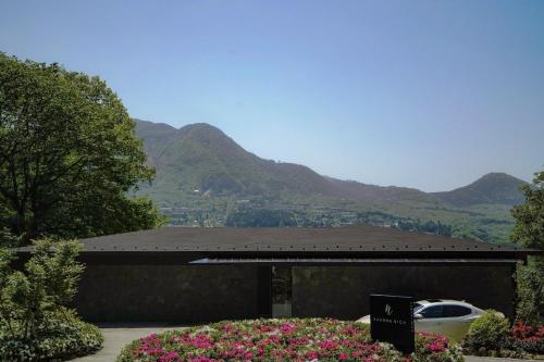 a building with a car parked in it with mountains in the background at HAKONE NICA in Hakone
