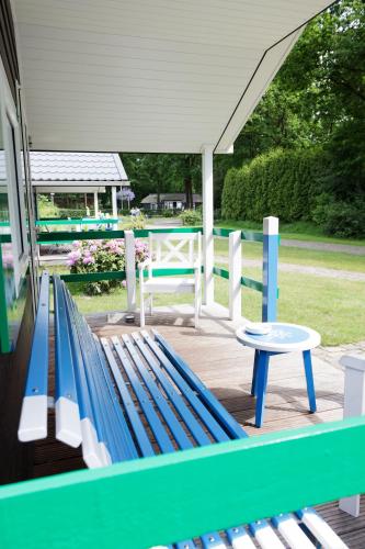 a blue bench sitting on a porch with a table at Familiecamping De Vossenburcht in IJhorst