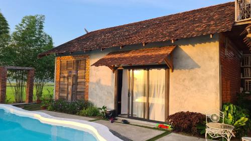 a house with a swimming pool in front of it at Classic Traditional Villa with Breathtaking View Pool WIFI in Pantai Cenang