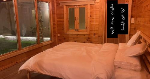 a bedroom with a bed with white sheets and windows at شاليهات ريموندا الريفيه الطائف in Taif