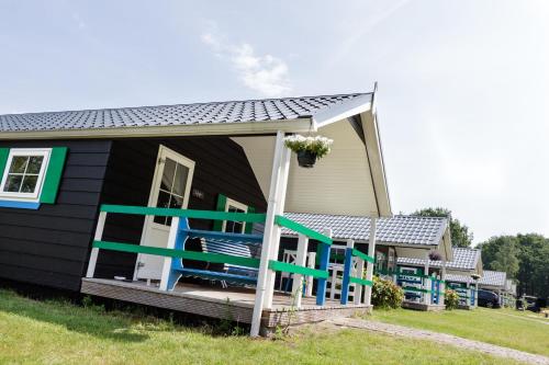 una casa negra con sillas azules en el porche en Familiecamping De Vossenburcht, en IJhorst